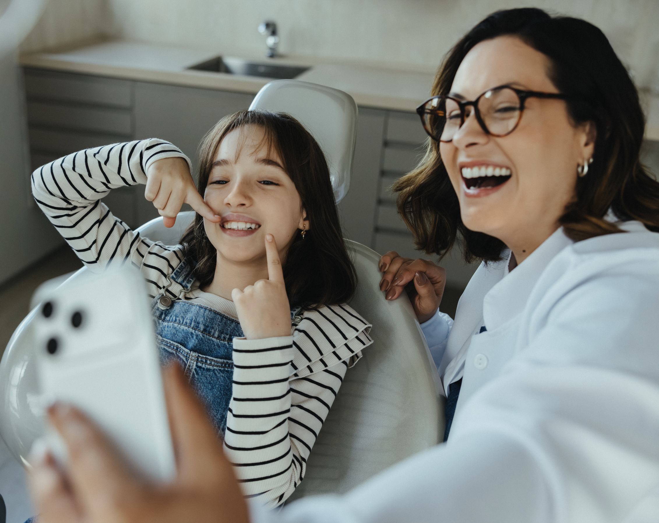A girl in the dental chair laughing with her dentist