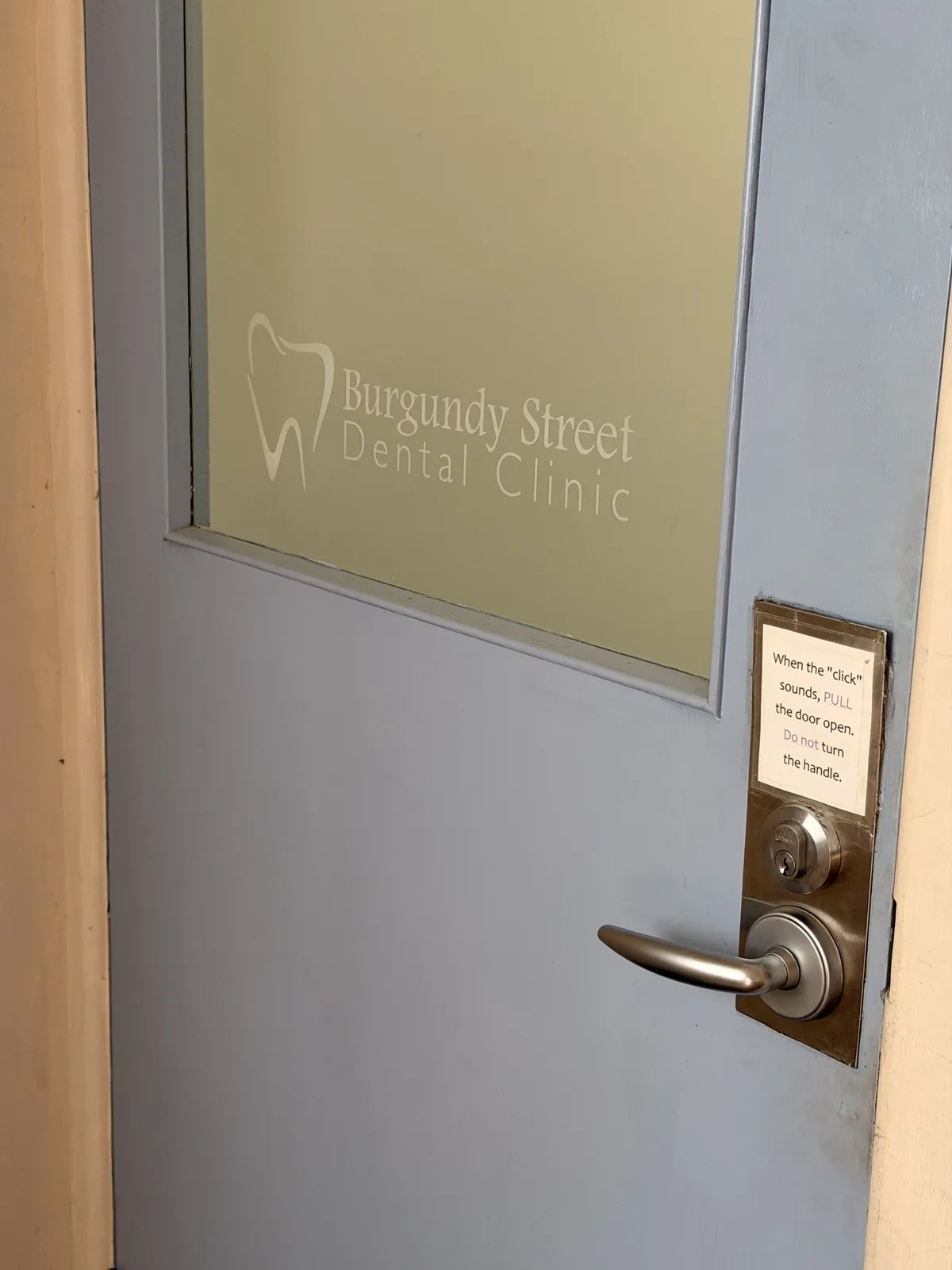 The frosted glass door to the practice with the Burgundy Street Dental Clinic logo