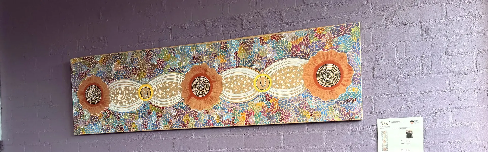 Aboriginal dot painting hanging on the lilac brick wall of the waiting room